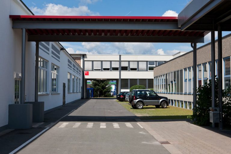 Gebäude und Parkplatzeinfahrt der Gebäude von Sirius Facilites GmbH