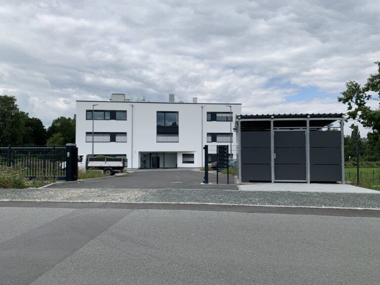 2 stöckiges modernes Bürogebäude, davor eine Einfahrt mit geparkten Autos